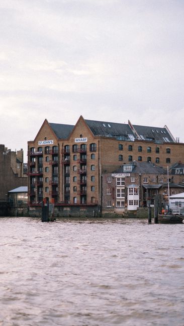 A high-angle view of a modern residential building complex along the waterfront at St Georges Wharf Waterloo, with tall multi-storey apartment blocks featuring large windows and balconies. The buildin